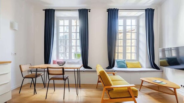 Ein modernes Wohnzimmer mit Holzboden, einer Couch, einem Esstisch mit Stühlen und einem Fernseher.