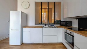 Eine moderne Küche mit weißen Schränken, einer Holz Arbeitsplatte, einem eingebauten Backofen und einer Mikrowelle.