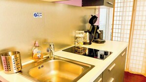 Une petite cuisine équipée d’un évier, d’une machine à café et d’un flacon de savon liquide.