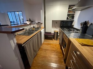 Eine moderne Küche mit Holzarbeitsplatte, Edelstahlgeräten und Blick auf den Wohnbereich.