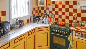 Une cuisine avec des meubles de couleur jaune, une cuisinière verte et un dosseret à carreaux.