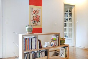 Une pièce avec une bibliothèque, une plante en pot et une porte qui donne sur une autre pièce.