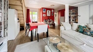 Un salon comprenant un coin repas, un escalier et une bibliothèque.