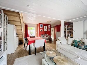 A living room with a dining area, a staircase, and a bookshelf. - Echoppe Bordelaise typique dans Bordeaux (Bordeaux)