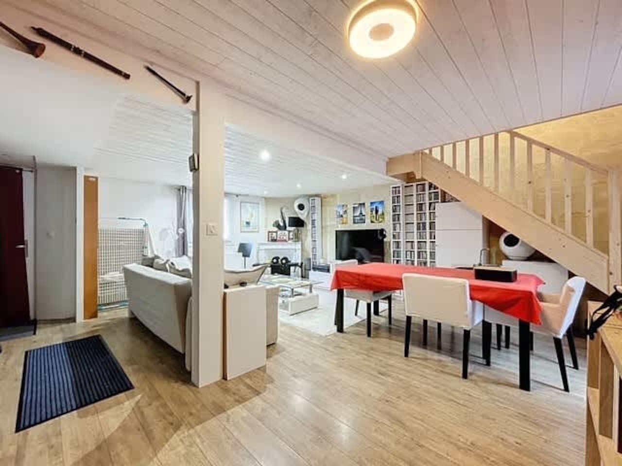 A modern interior with a dining area, a sofa, and a staircase.
