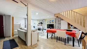 A modern interior with a dining area, a sofa, and a staircase.