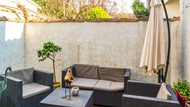 Un espace extérieur aménag é avec des meubles en osier, une petite table et une statue d’oiseau décorative.