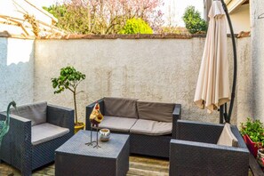 Un espace extérieur aménagé avec des meubles en osier, une petite table et une statue d’oiseau décorative.