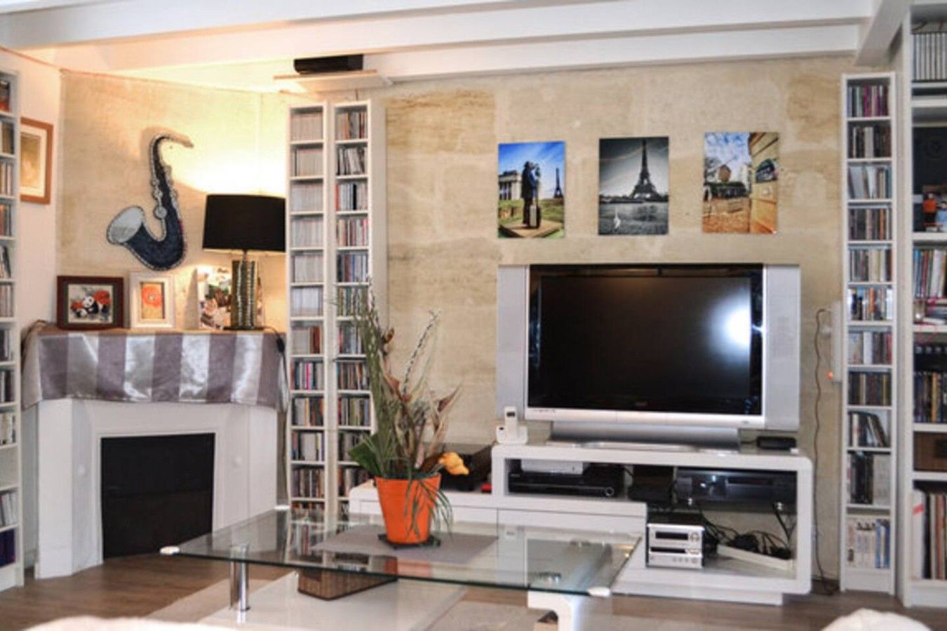 Un salon avec une cheminée, un téléviseur à écran plat et des étagères à livres.