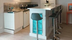 Une cuisine compacte dotée d’un îlot central, de tabourets de bar et d’une cuisinière moderne.