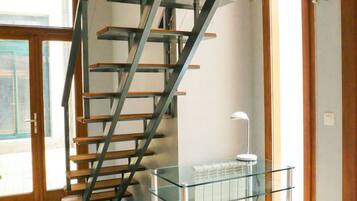 Un intérieur moderne avec un escalier en colimaçon, une table en verre et un tabouret blanc.