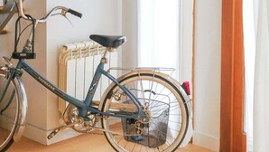 Une pièce avec un vélo bleu, un escalier en bois et un radiateur.