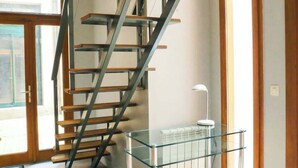 Un intérieur moderne avec un escalier en colimaçon, une table en verre et une chaise blanche.