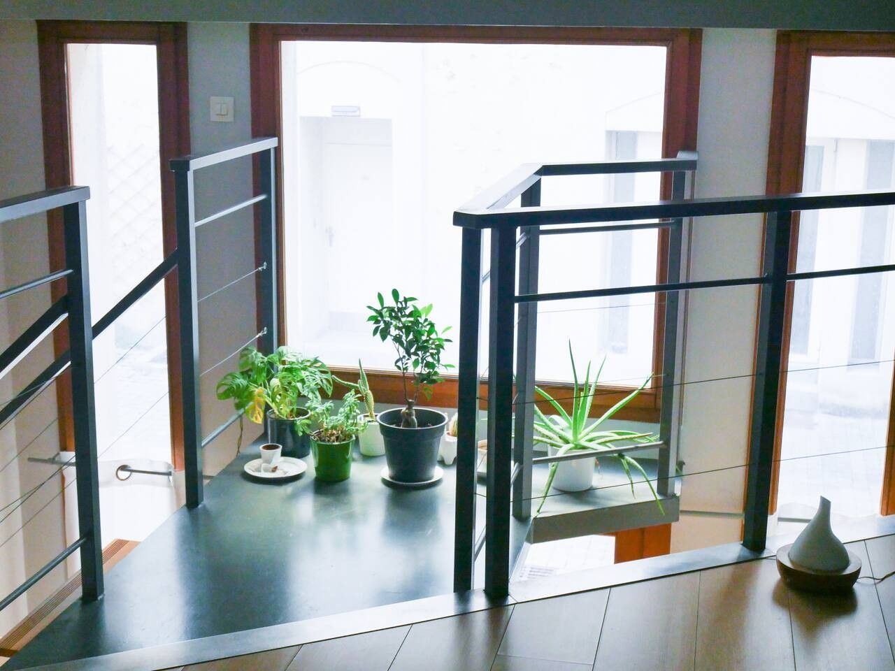 Un intérieur moderne avec un balcon, des plantes en pot et une vue sur la ville.