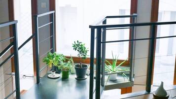 Un intérieur moderne avec un balcon, des plantes en pot et une vue sur la ville.