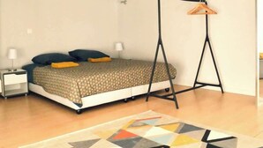 Une chambre à coucher avec un lit, une table de chevet, un fauteuil suspendu et un tapis à motifs.