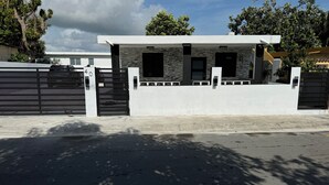 Una casa moderna con fachada blanca, una reja negra y un camino de entrada pavimentado.