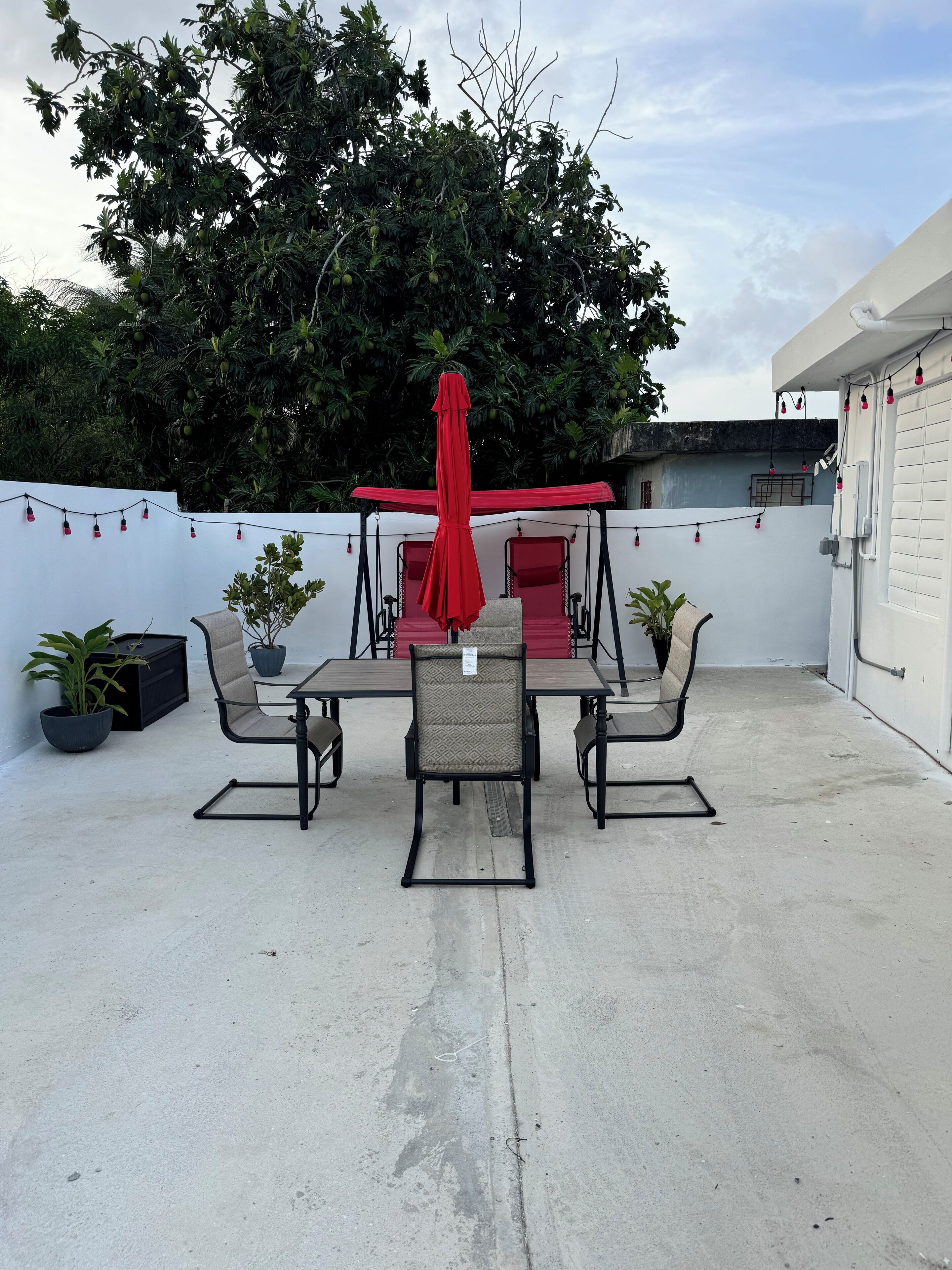 Une terrasse avec une table et des chaises, une balançoire et des plantes en pot.