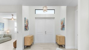 Un couloir moderne avec une porte blanche, des meubles en bois et des œuvres d’art accrochées aux murs.