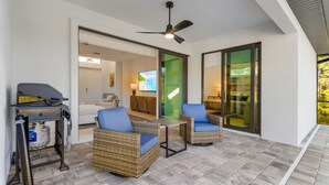 Un espace patio aménagé avec des meubles en osier, un barbecue et un téléviseur.