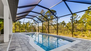 Une piscine dotée d’une structure de toit aux lignes géométriques, entourée d’une terrasse dallée de pierres.