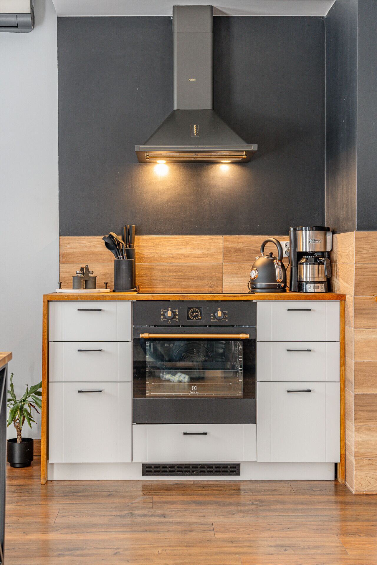 Une cuisine moderne équipée d’un four encastré, d’une hotte aspirante et d’une machine à café.