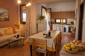 A cozy living room with a dining area, a kitchen, and a view of the sea.