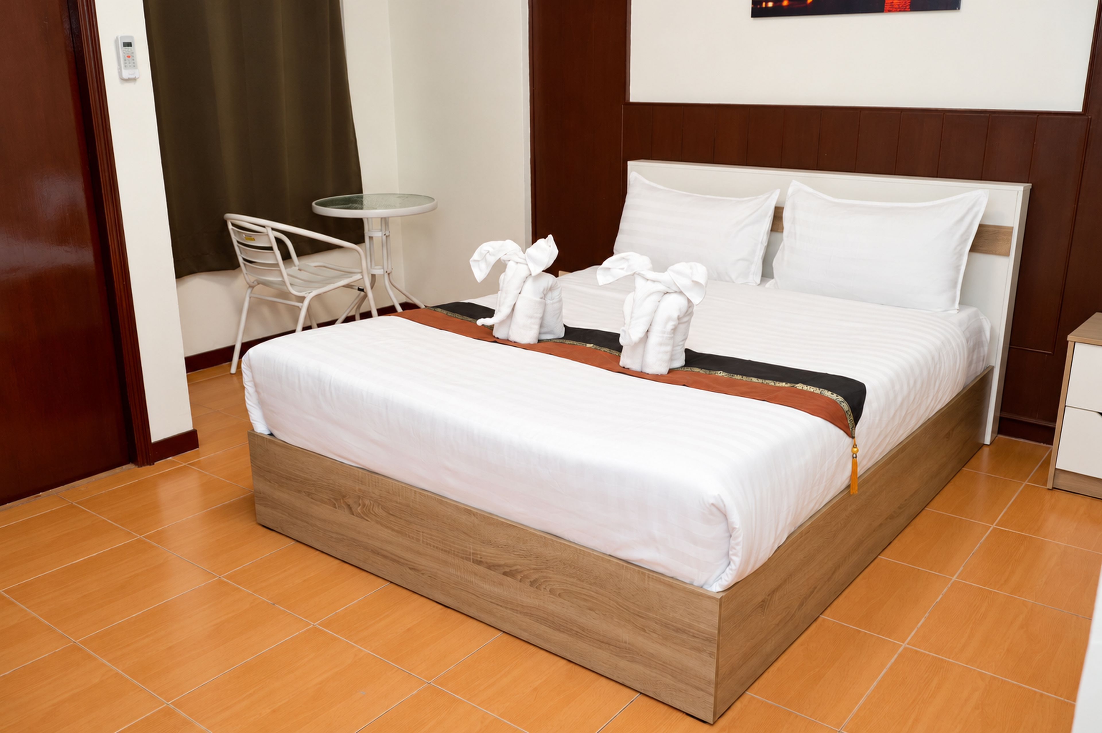 A hotel room with a bed, a small table, a chair, and a wall-mounted phone.