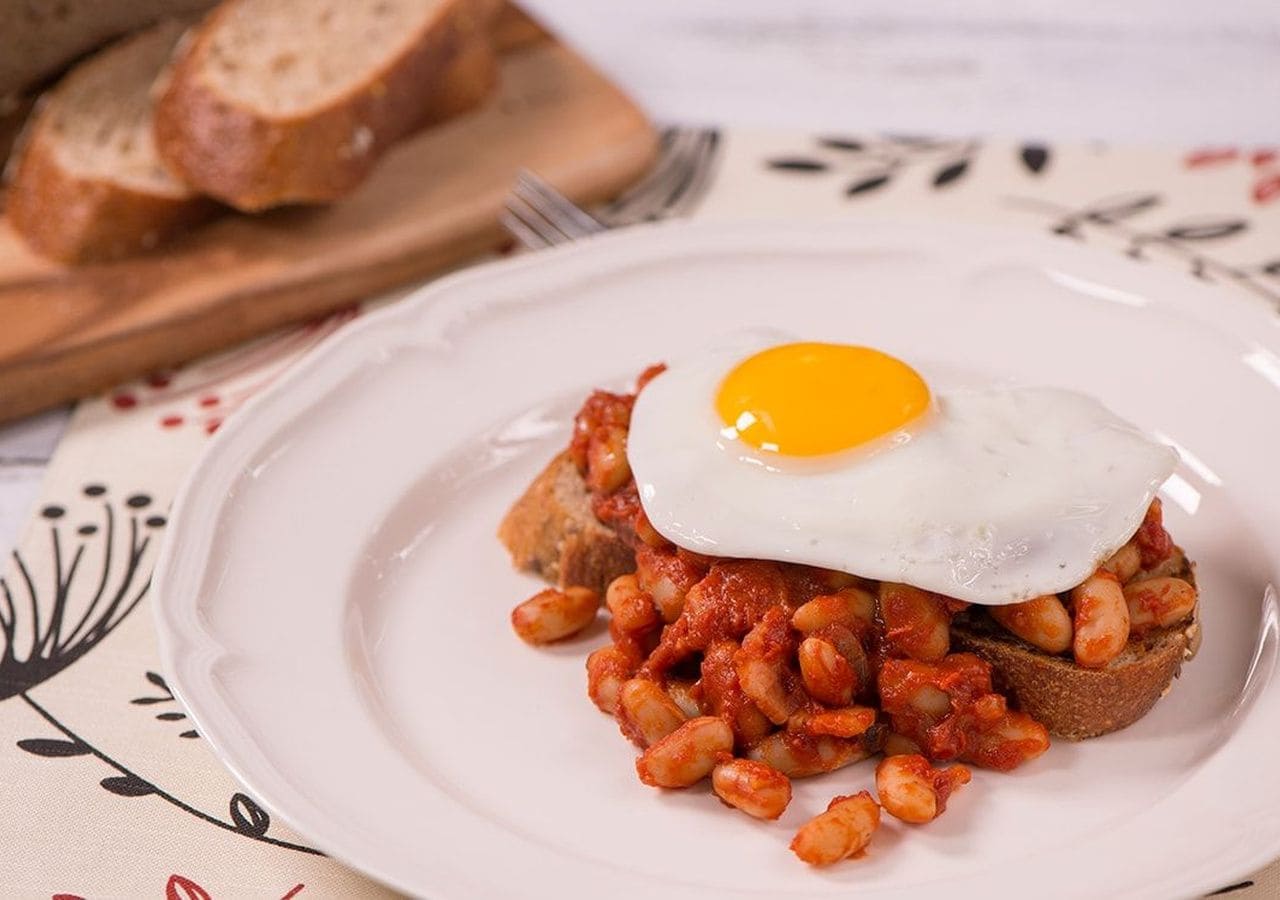 A plate with beans and a fried egg on toast.