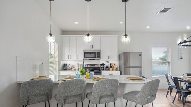 A modern kitchen with white cabinets, a central island with bar stools, and pendant lighting. - Your Inner-City Sanctuary: 3BR/2BA Near Riverwalk (San Antonio)