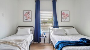 A twin bedroom with two beds, a small table, and a window with blinds. - Your Inner-City Sanctuary: 3BR/2BA Near Riverwalk (San Antonio)
