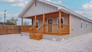 A single-story building with a wooden porch and a staircase leading to the entrance. - Your Inner-City Sanctuary: 3BR/2BA Near Riverwalk (San Antonio)