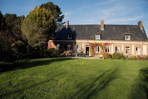 A large brick house with a well-maintained lawn and a patio area with outdoor furniture.