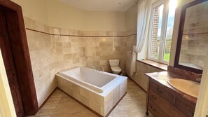 A bathroom with a large bathtub, a toilet, and a vanity with a mirror. - Elegant Normandy Country House – 5 Minutes from the Sea (Ouainville)