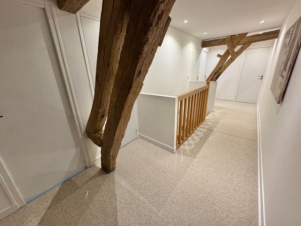 A hallway with a wooden beam structure, a white door, and a small wooden counter.