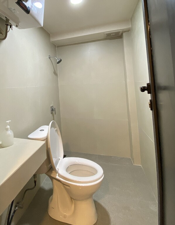 A bathroom with a toilet, a shower, and a sink.