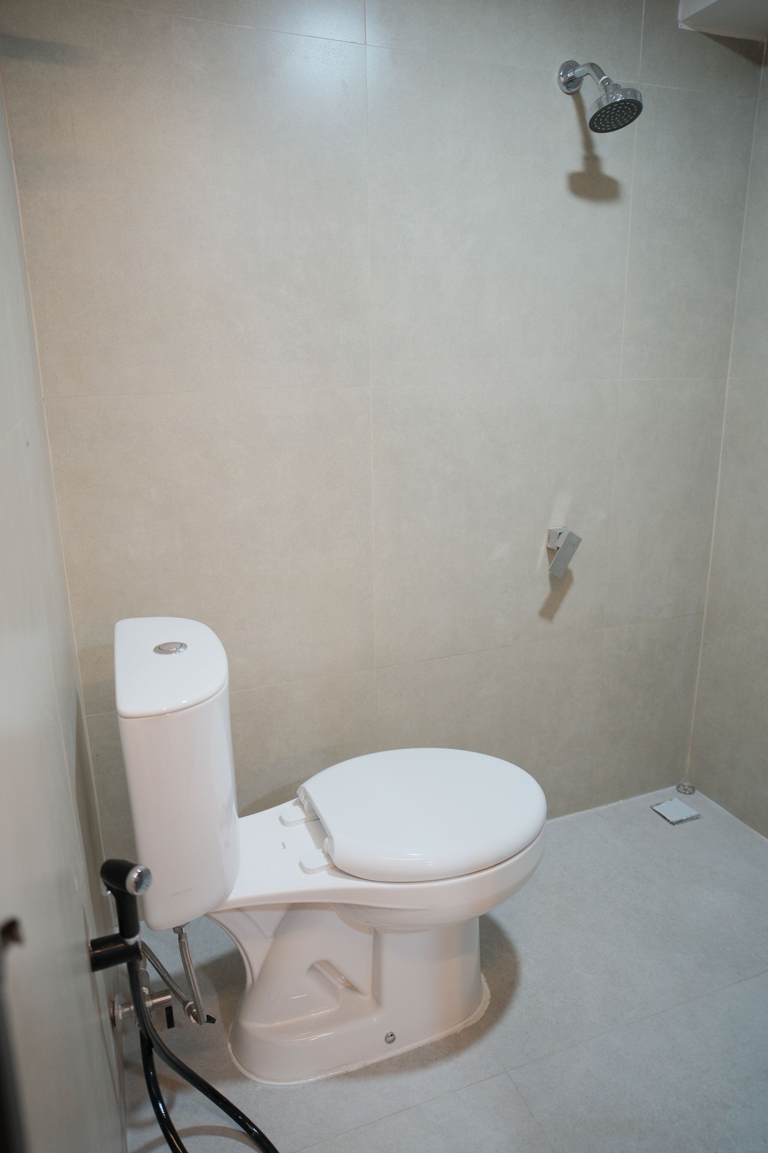 Un baño con inodoro, ducha y dispensador de papel higiénico.