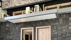 Ένα σύγχρονο σπίτι με πρόσοψη από πέτρα, δύο ξύλινες πόρτες και ένα αυτοκίνητο σταθμευμένο στην αυλή.