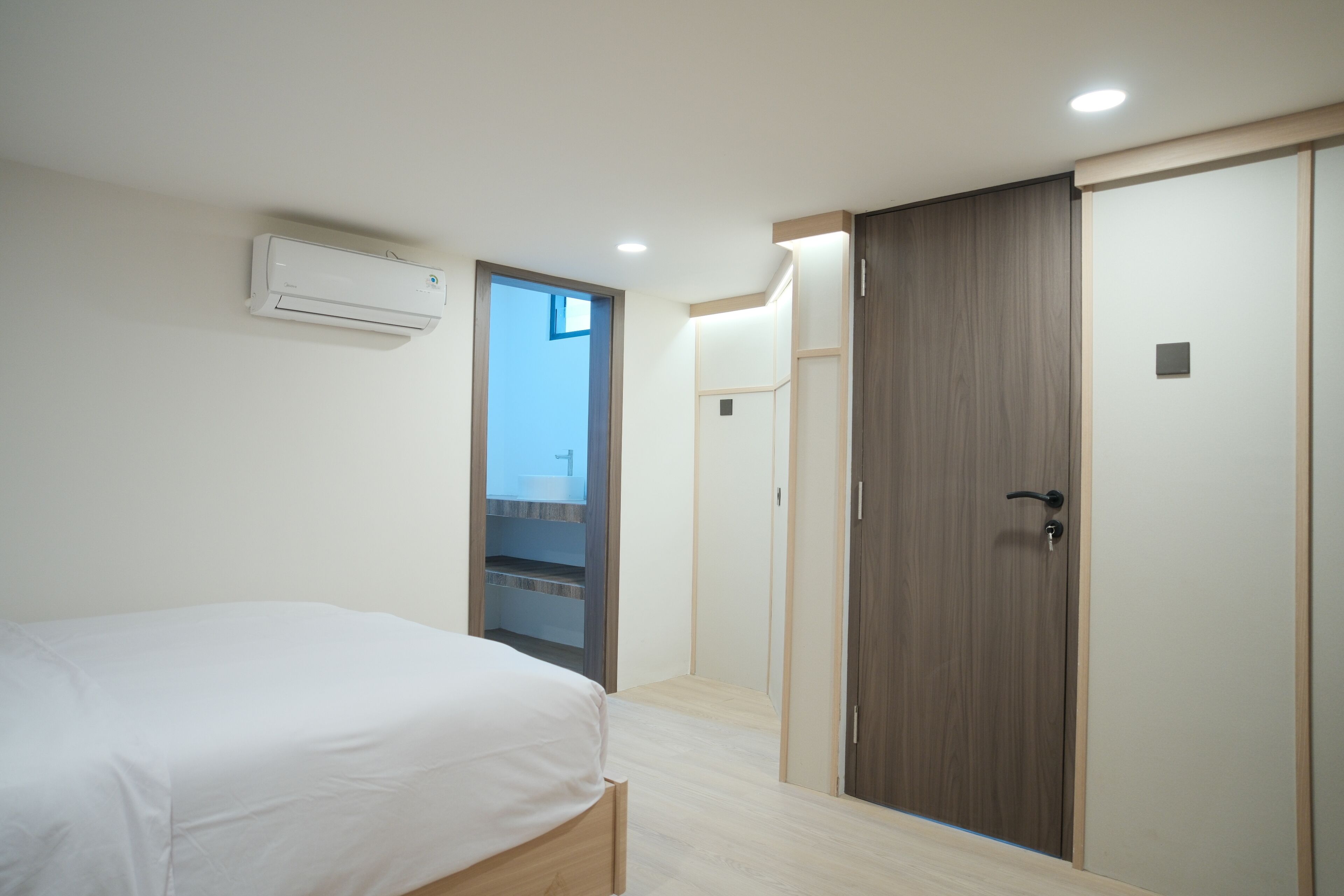 A bedroom with a bed, a wardrobe, and an air conditioning unit.