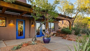 A building with a blue door, a wooden pergola, and a cactus plant. - 2 bed 2 bath in the Kayenta Art Village W/Views of the red rock cliffs. (Ivins)