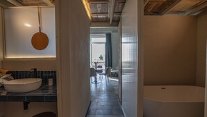 Een moderne badkamer met een groot bad, een ronde spiegel en een wastafel.