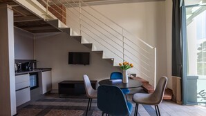 Een moderne keuken met een ingebouwde oven, een eethoek met een ronde tafel en stoelen, en een trap naar een hoger gelegen verdieping.
