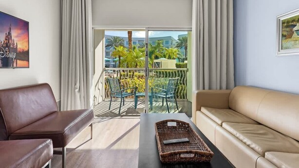 Habitación de hotel con balcón, sofá, sillón y una mesa con bandeja.
