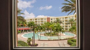 Un hotel con piscina, palmeras y un edificio de varios pisos.