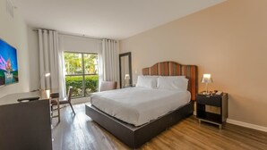 Habitación de hotel con una cama grande, un escritorio, una silla, un televisor y una ventana con cortinas.
