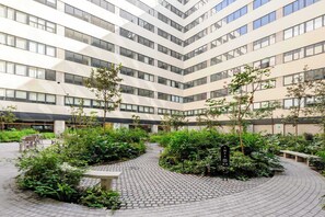 A multi-story building with a courtyard featuring a brick pathway, greenery, and seating areas. - w* | Sophisticated 3BR in Cuauhtemoc w/ Pool (Ciudad de México)