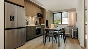 Eine moderne Küche mit Edelstahlgeräten, ein Essbereich mit Tisch und Stühlen sowie ein großes Fenster für natürliches Licht.