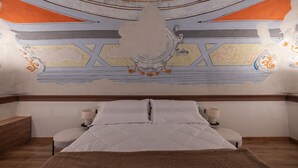 Een slaapkamer met een bed, twee nachtkastjes en een decoratief schilderwerk op het plafond.