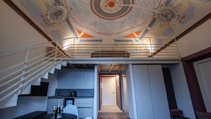 Een modern interieur met een trap naar een entresol, een keukenhoek en een gang.