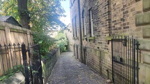 Une ruelle étroite aux murs de briques, avec une porte en métal et une boîte aux lettres.